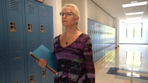 Slow motion front view of teacher walking down a hallway in an empty school Stock Footage 138961988