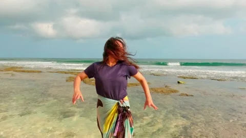 Slow motion front view of woman fixing windblown hair on tropical ocean beach Video stock 345391999