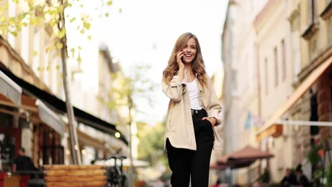 Slow motion front view of a young beautiful blonde woman walking and calling on Stock Footage 144567961