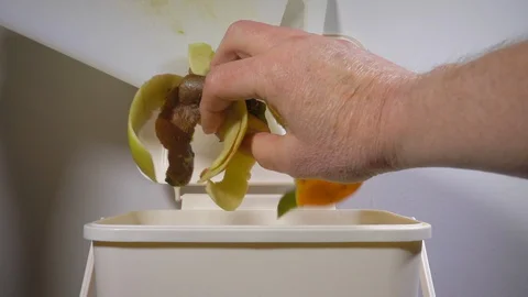 Slow motion - Fruit peelings being dropped into a small plastic trash can / bin. Stock Footage 129154231