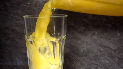 Slow motion – fruit smoothie being poured from a jug to a glass tumbler. Stock Footage 102032129