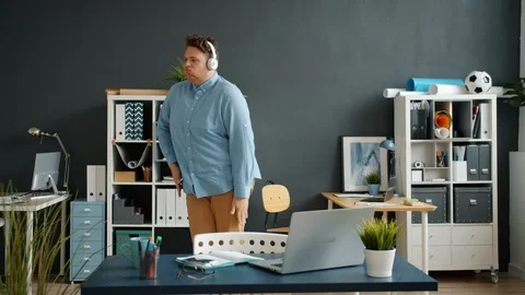 Slow motion of funny employee dancing in office room wearing headphones Stock Footage 123017674