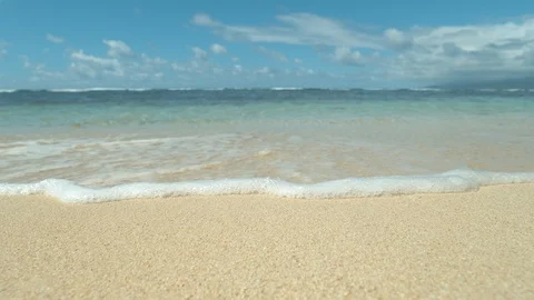 SLOW MOTION: Gentle ocean wave coming from the distance washes white sand shore. Stock Footage 87487297