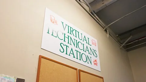 Slow-motion gimbal shows 'Virtual Technicians Station' sign with furniture Vidéo 318521696