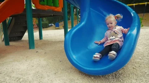 SLOW MOTION: girl three-years comes down from the slide  on the playground. Stock Footage 80192012