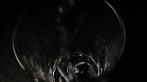 Slow motion. In a glass on a black table water flows Video stock 74761625
