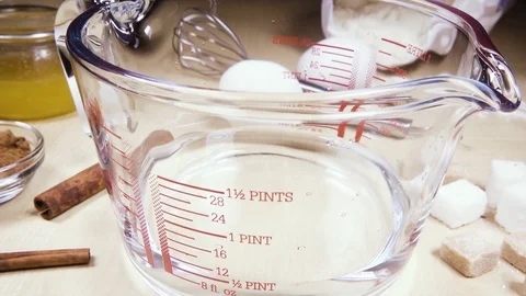 Slow motion glass measuring cup on the table near the ingredients Stock Footage 95639725
