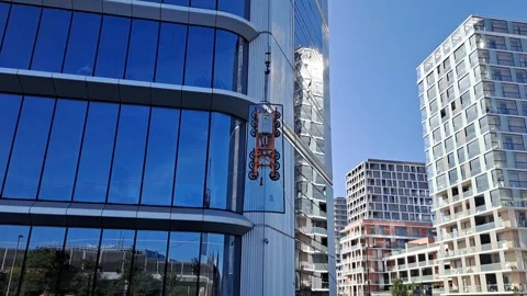 Slow motion of glass panel hoisting stabilized by BMU guide ropes Stock Footage 337359365