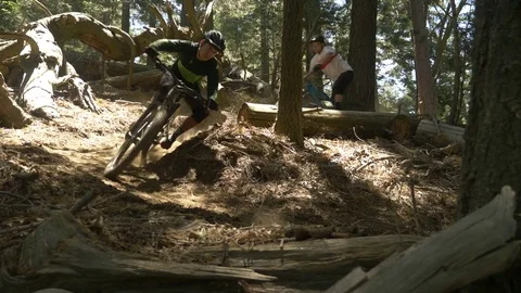 Slow motion glide cam shot of two guys mountain biking on a sharp S turn. Video stock 77582512