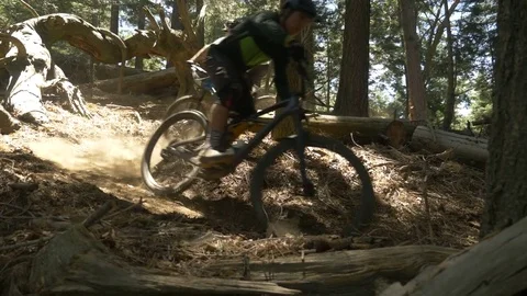 Slow motion glide cam shot of two guys mountain biking on a sharp turn. Video stock 77602932