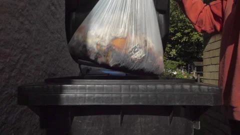 Slow motion - Gloved hand lifting bin lid, dropping food waste bag, closing lid. Video stock 162164979