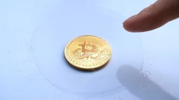 Slow motion - gold btc bitcoin coin inside soap bubble popped by mans finger  Stock Footage 85763020