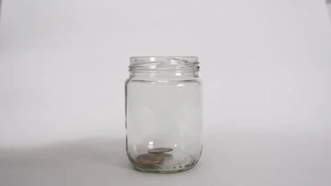 Slow motion of gold coins dropping into a glass jar on white background Stock Footage 317107860
