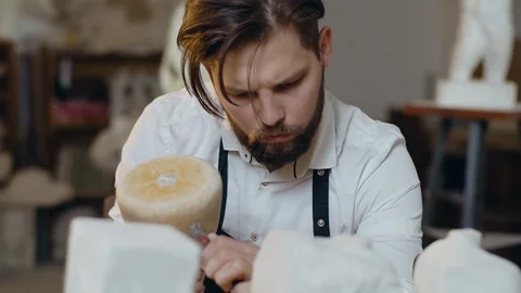Slow motion of good-looking focused on his work bearded young sculptor which Video stock 123278818