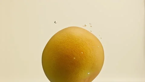 Slow motion grapefruit falls into the water with air bubbles Stock Footage 148180326