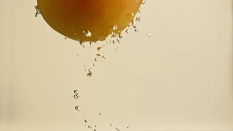 Slow motion grapefruit falls into the water with air bubbles Stock Footage 148180524
