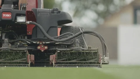 Slow motion of grass mowing machine trimming grass on football field Stock Footage 104769031