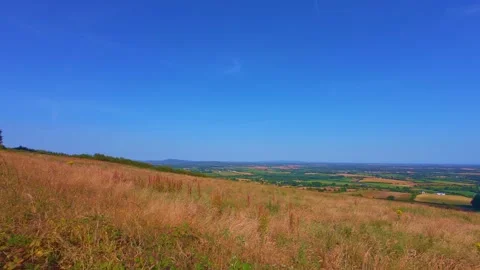 Slow motion grassy hill slope under blue sky with light clouds Stock Footage 340440906