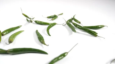 Slow motion green birdseye chillis thrown onto a white surface, group cluster Stock Footage 88340754