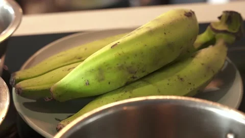 Slow motion green cooking bananas on the kitchen table. Fried plantain tostones Stock Footage 232946955