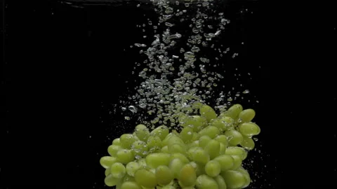 Slow motion green grapes falling into transparent water on black background Stock Footage 161885490