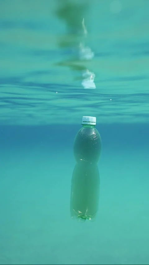 Slow motion, Green plastic bottle drifting under surface of blue water  Video stock 237230394