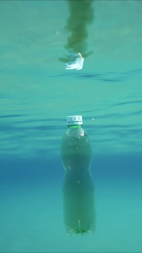 Slow motion, Green plastic bottle drifting under surface of blue water. Plastic Stock Footage 237939150