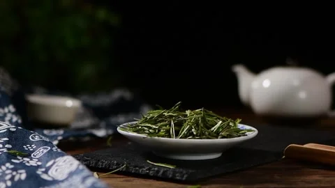 Slow Motion Green Tea Leaves Falling on Plate in Dark Moody Lighting Stock Footage 340302904