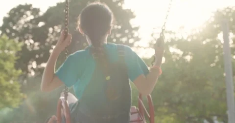 Slow motion of a gril on a swing at the playground -  with the sunset  Stock Footage 77963989