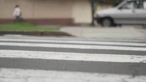 Slow motion ground level city crosswalk with cars passing by Stock Footage 82245608