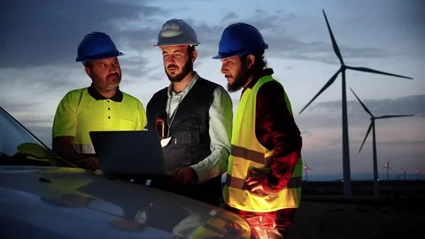 Slow motion. Group of windmill engineers using a laptop to talk about the Stock Footage 240293343