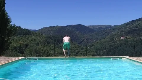 Slow motion of a guy back flip jumping into a swimming pool with mountains view Stock Footage 89782338