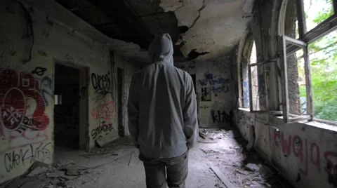Slow motion of a guy with hood walking through abandoned building 스톡 동영상 58613775