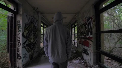 Slow motion of a guy with hood walking through abandoned building Stock Footage 58614937