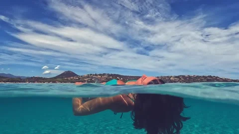 Slow-motion half underwater view of woman floating on sea Видео 279860783