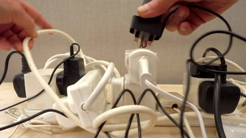 Slow motion - Hand adding another plug to an overloaded power extension board. Stock-Footage 195430425