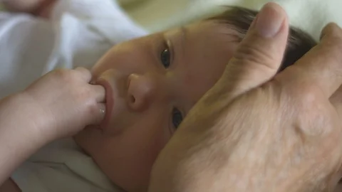 Slow motion of hand caressing head of baby who is sucking fingers Stock Footage 114103515