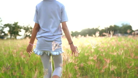Slow motion hand of child and grass field on sunny Stockbeeldmateriaal 141861103
