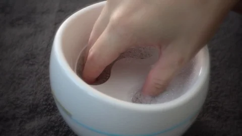 Slow motion: Hand dipping into a portable nail spa. Video stock 78932809