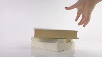 Slow motion of hand dropping a book onto a pile of books Stock Footage 85363093