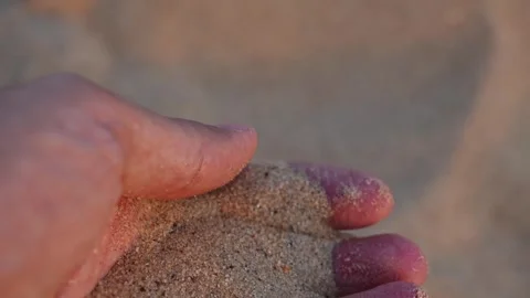 Slow motion hand letting fine sand fall through fingers at sunset Stock Footage 345293491
