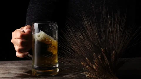 Slow-motion of Hand movement holding a beer glass on a black background Stock Footage 145275984