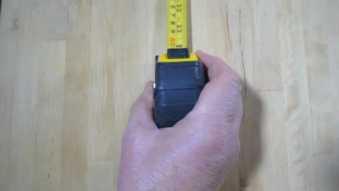 Slow motion – Hand pulling a tape measure across a wooden surface. Video stock 119663857