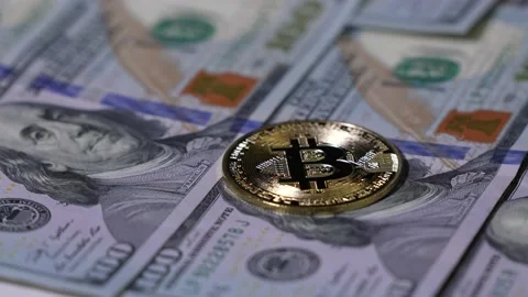 Slow motion. Hand puts the Bitcoin BTC coin on 100 dollars. Digital coin Stock Footage 169641699