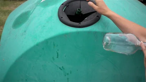 Slow motion hand throws empty glass bottle in trash can. Stock Footage 114293995