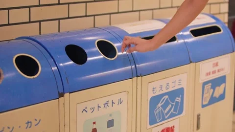 Slow motion of hand tossing waste into row of clean blue recycling bins Stock Footage 322638200