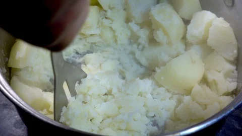Slow motion – Hand using a steel tool to mash boiled potatoes in a pan. 스톡 동영상 104107216