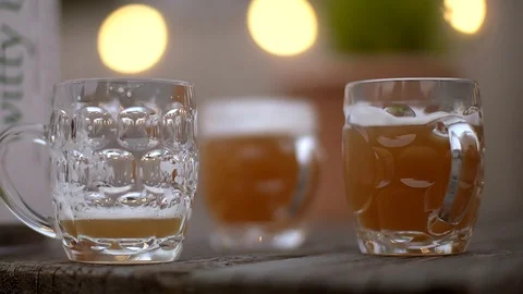 Slow motion handheld shot of 3 beers on a pub garden table Stock Footage 87857687