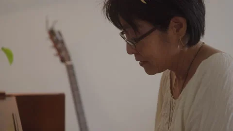 Slow motion handheld shot of focused old asian female musician playing piano Stock Footage 208793004