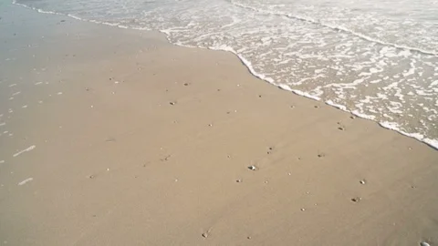 Slow motion handheld shot of gentle waves lapping pristine sand Stock Footage 119533743